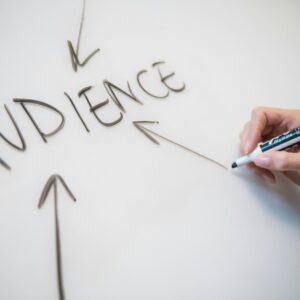 Hand writing the word 'AUDIENCE' on a whiteboard with arrows pointing towards it, highlighting focus on audience