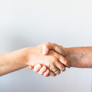 Two people shaking hands as a gesture of agreement and cooperation.